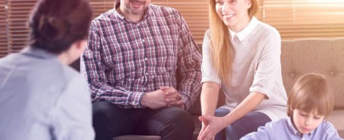 A family is sitting on a couch and talking to each other
