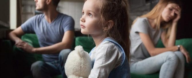 A young girl sitting on a couch with a teddy bear