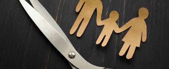 A pair of scissors next to a paper cut out of a family