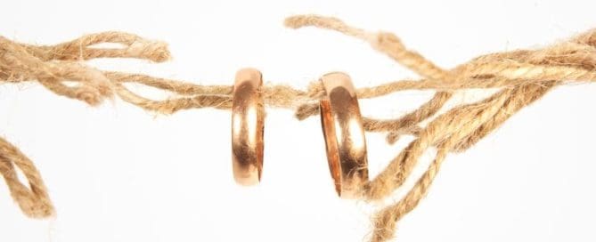 Two wedding rings hanging on a twine with a white background.