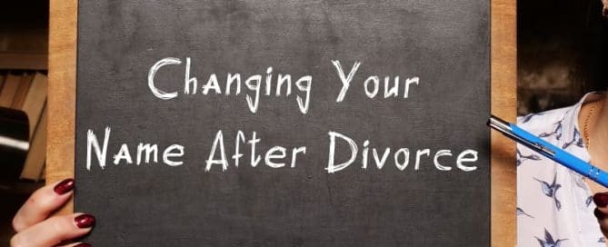 A person holds a chalkboard with the text "Changing Your Name After Divorce" written on it.