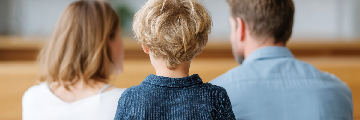Family Law Custody A child with blonde hair sits between two adults, seen from behind. The scene subtly reflects the complexities of family legal issues in California, with all three facing away from the camera.